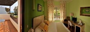 a bedroom with green walls and a bed and a desk at Hotel las Calas in Agua Amarga