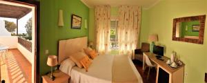 a bedroom with green walls and a bed and a desk at Hotel las Calas in Agua Amarga