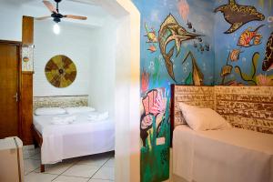 a bedroom with two beds and a mural of fish at Pousada Maanaim 2 in Ubatuba