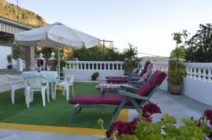 eine Terrasse mit einem Tisch, Stühlen und einem Sonnenschirm in der Unterkunft Casa Los Barranquillos in Lanjarón