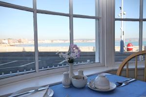 a table with a vase of flowers in a room with a window at The Anchorage in Weymouth