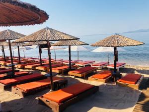 a beach with many chairs and umbrellas and the ocean at Ofrinio Beach Cosy & Relaxing in Orfánion
