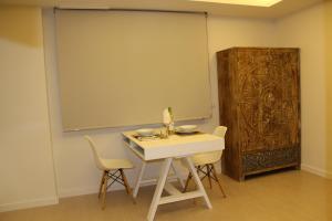 Habitación con mesa blanca, sillas y pantalla grande. en Romantic Loft Ventura, en Tarifa