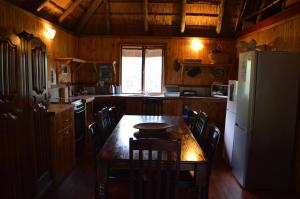 a kitchen with a table with chairs and a refrigerator at Lion Tree Bush Lodge in Marloth Park