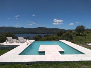 a swimming pool with two chairs and a body of water at Un Buen Lugar in Villa Parque Siquiman