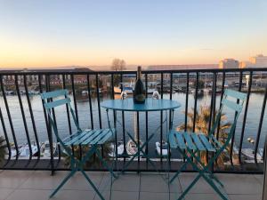 - une table avec une bouteille de vin et 2 chaises sur un balcon dans l'établissement L'Escale Sètoise, à Sète