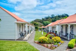 una fila de casas blancas con techos rojos en Coromandel Cottages en Coromandel Town