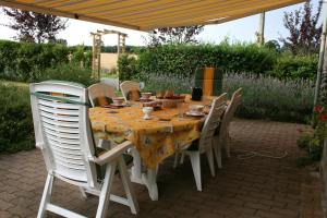 mesa con sillas blancas y mantel amarillo en Herbages de Beauvais en Orgères-la-Roche