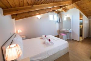 a bedroom with a white bed and a wooden ceiling at Lefkogea Villas & Apartments in Tsoukaladhes