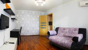 チフヴィンにあるУютный Тихвин апартаменты 1 микрорайон д 50のリビングルーム(紫色のソファ、テレビ付)
