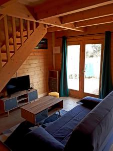 a living room with a couch and a wooden staircase at Gîte le châlet des milles et un chemins in Castelnou
