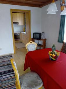 a dining room with a red table with a bowl of fruit on it at Berningerhof in St. Wolfgang