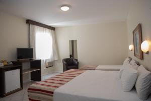 a hotel room with a bed and a television at Hotel Ryan by Pires - Balneario Camboriu in Balneário Camboriú