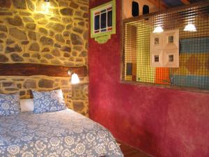 1 dormitorio con cama y pared de piedra en Jardines del Robledo-Albar, en San Miguel del Robledo