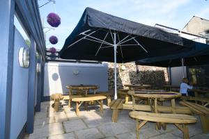 un patio con mesas, sillas y una sombrilla en Rose and Crown Hotel, en Carmarthen