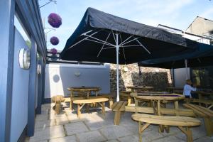 a patio with tables and chairs and an umbrella at Rose and Crown Hotel in Carmarthen