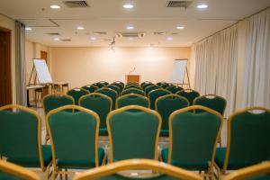una sala de conferencias con sillas verdes y un podio en Gloria Garden Suites, en Macaé