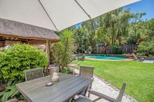 a wooden table and chairs in a backyard with a pool at Sitatunga Guest Lodge - Sandton - Airport Shuttle - Solar & Borehole in Johannesburg +7 photos