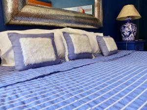 Cama con sábanas y almohadas azules y blancas en Casa Carly, en San Miguel de Allende