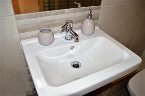 a white bathroom sink with two cups on it at Downtown Apartments DeLuxe in Győr