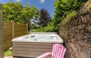 bañera de hidromasaje con silla rosa junto a una pared de piedra en La Maison Bizienne Guérande en Guérande