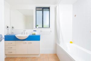 a bathroom with a sink, mirror and tub at Belaire Place in Caloundra