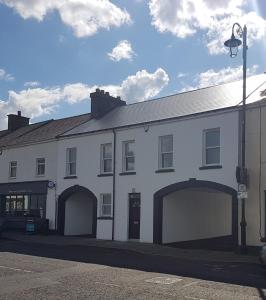 ein weißes Gebäude mit zwei Garagentüren auf einer Straße in der Unterkunft The T House in Bushmills