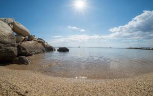a beach with rocks and the sun in the sky at Assano Seafront Luxury in Nikiti