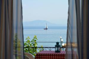 a sailboat in the ocean viewed from a window at Eros Beach Hotel in Benitses