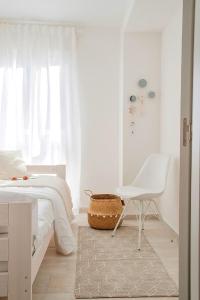 ein Schlafzimmer mit einem weißen Bett und einem weißen Stuhl in der Unterkunft City Valencia Beach 360 in Valencia