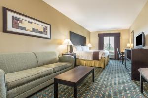 a hotel room with a couch and a bed at Days Inn & Suites by Wyndham Mineral Wells in Mineral Wells