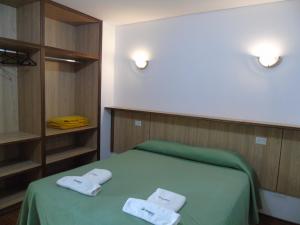 Un dormitorio con una cama verde con toallas. en Urunday Apart Hotel en Posadas