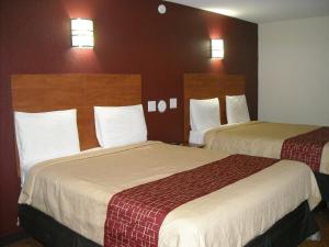 een hotelkamer met 2 bedden en 2 verlichting aan de muur bij Bastrop Inn in Bastrop
