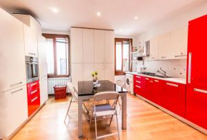 a kitchen with red cabinets and a table and chairs at Ca' Lunetta - 5' from St. Mark Square in Venice