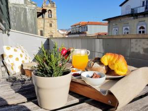 Braga Bells Guesthouse في براغا: طاولة مع طبق من الطعام وكأس من عصير البرتقال