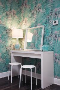 a desk with a mirror and two stools in a room with a palm wallpaper at The Steady in Los Angeles