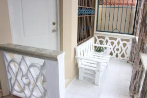 weranda z białą ławką i drzwiami w obiekcie Elisa Furnished Apartments (Puerto Plata City) w mieście Puerto Plata