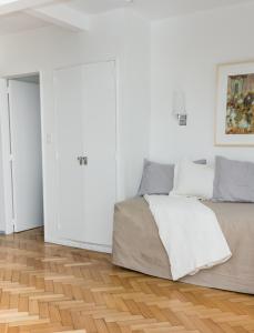 1 dormitorio blanco con 1 cama y suelo de madera en Optimus BA | Arenales en Buenos Aires