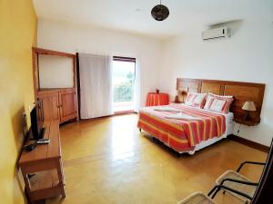 um quarto com uma cama, uma secretária e uma janela em Memorial Ilhabela residencial em Ilhabela