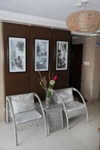 ドゥマゲテにあるオプティマム ペンション ハウスの籐の椅子2脚、花瓶付きテーブル