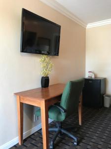 a desk with a chair and a television on a wall at Fullerton Lodge in Fullerton