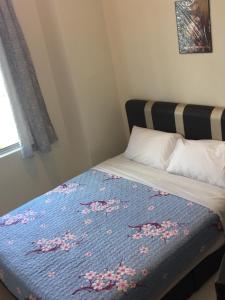 a bed with a blue blanket with pink flowers on it at Cameron Cactus Apartment @ Pangsapuri Kaktus in Brinchang