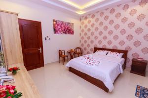 um quarto com uma cama com lençóis brancos e almofadas vermelhas em VẠN LỘC HOTEL em Can Tho