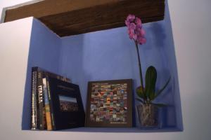 un estante con libros y un jarrón con una flor en Casa il Girasole con piscina nelle Marche, en Macerata