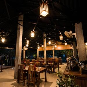 ein Restaurant mit Holztischen, Stühlen und Lampen in der Unterkunft Sigiri Asna Nature Resort in Sigiriya