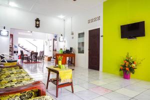 a living room with a green wall and a tv at OYO 433 Nelvi Guest House Syariah in Padang