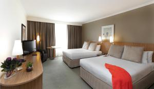 a hotel room with two beds and a television at Mercure Sydney Parramatta in Sydney