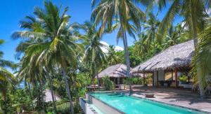 a villa with a swimming pool and palm trees at Moro Ma Doto in Busobuso