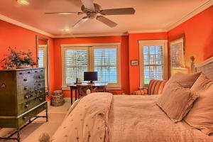 Schlafzimmer mit orangefarbenen Wänden und einem Bett mit Deckenventilator in der Unterkunft Lake Escape in Charlevoix