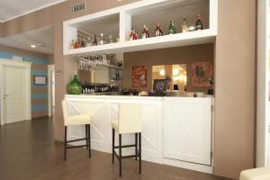 a bar with white cabinets and bar stools at Hotel Margherita in Monterosso al Mare
